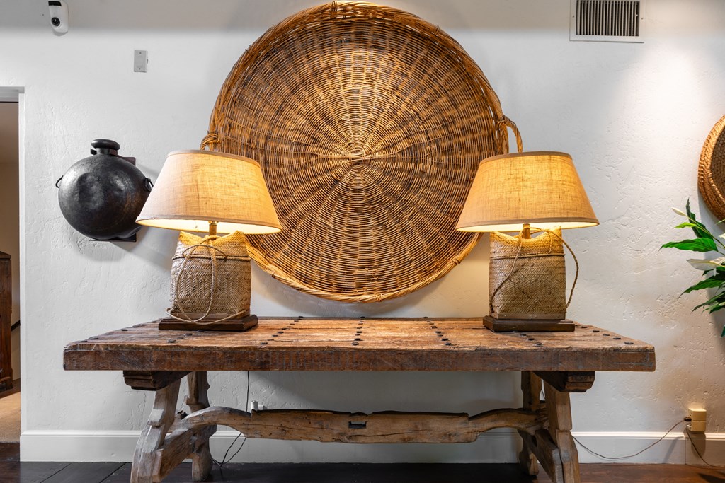 two lamps on a wooden table in front of a wicker chair