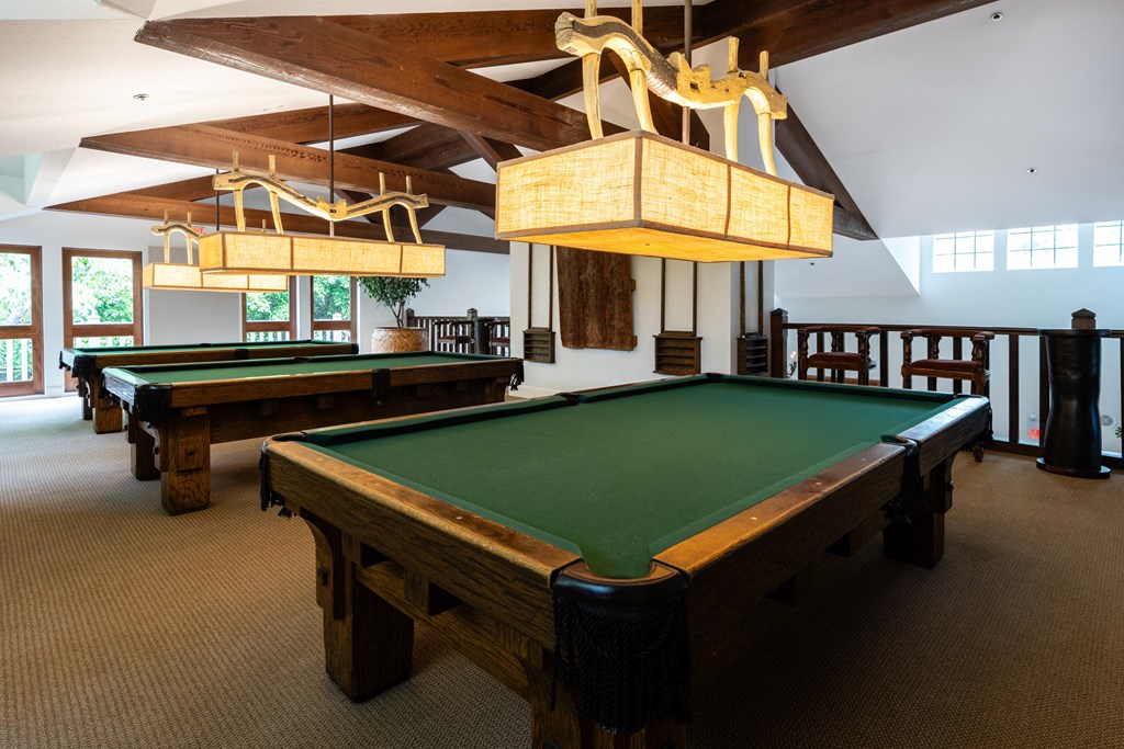 two pool tables in the center of a room with two chandeliers