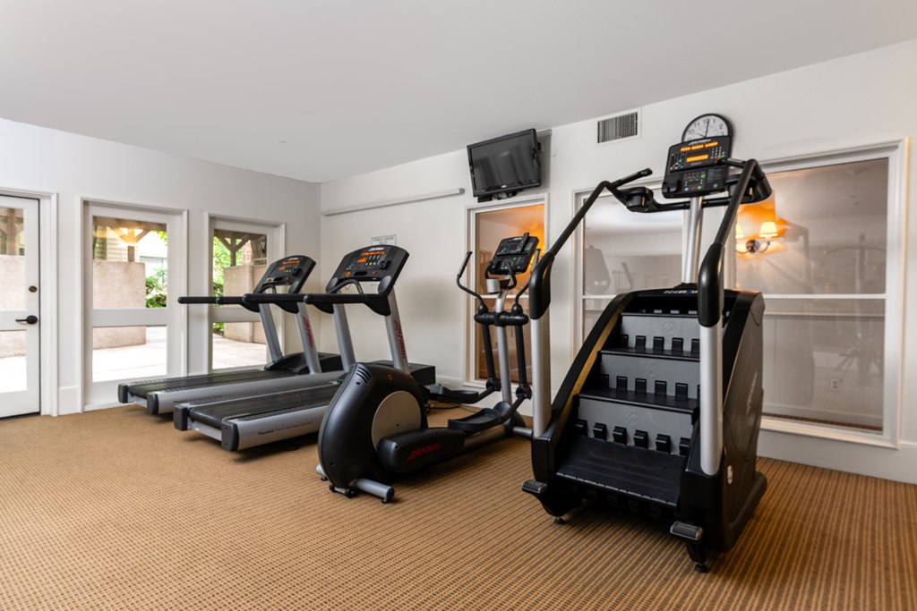 two treadmills and other exercise equipment in a room with glass doors