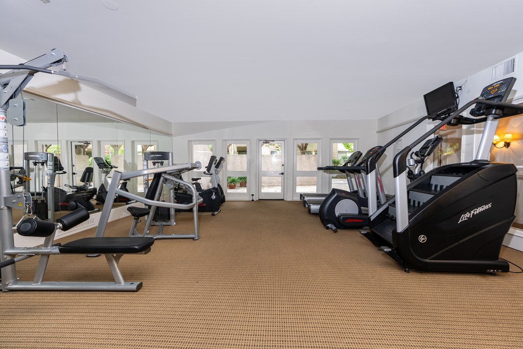 a gym with various exercise equipment in a room with windows