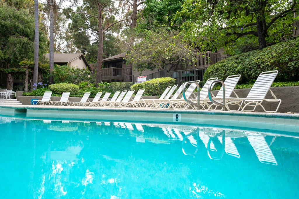a swimming pool with white lounge chairs