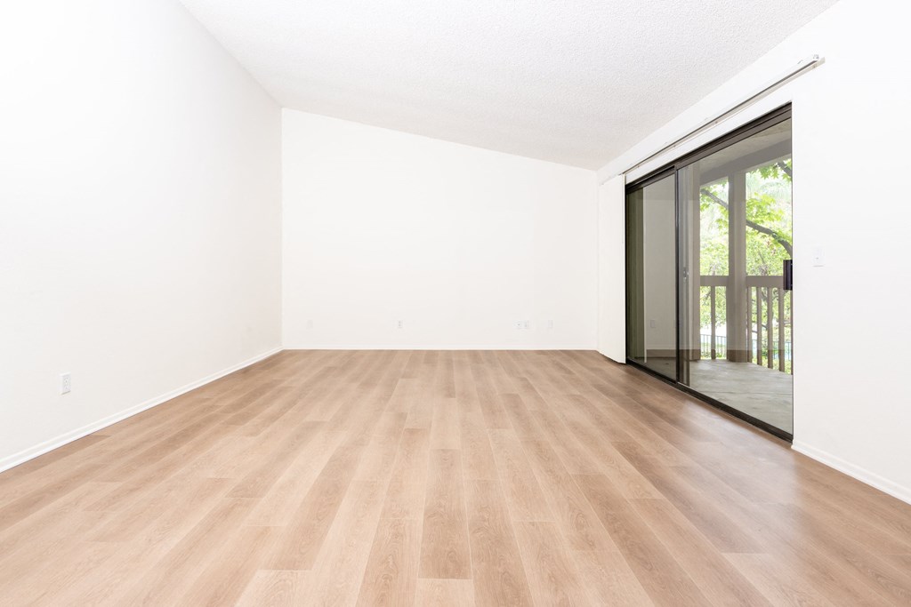 an empty living room with a wood floor and a sliding glass door