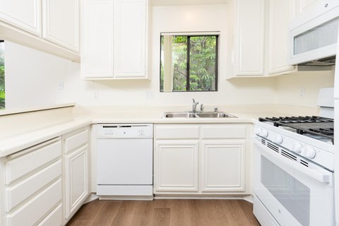 a kitchen with white cabinets and white appliances and a sink