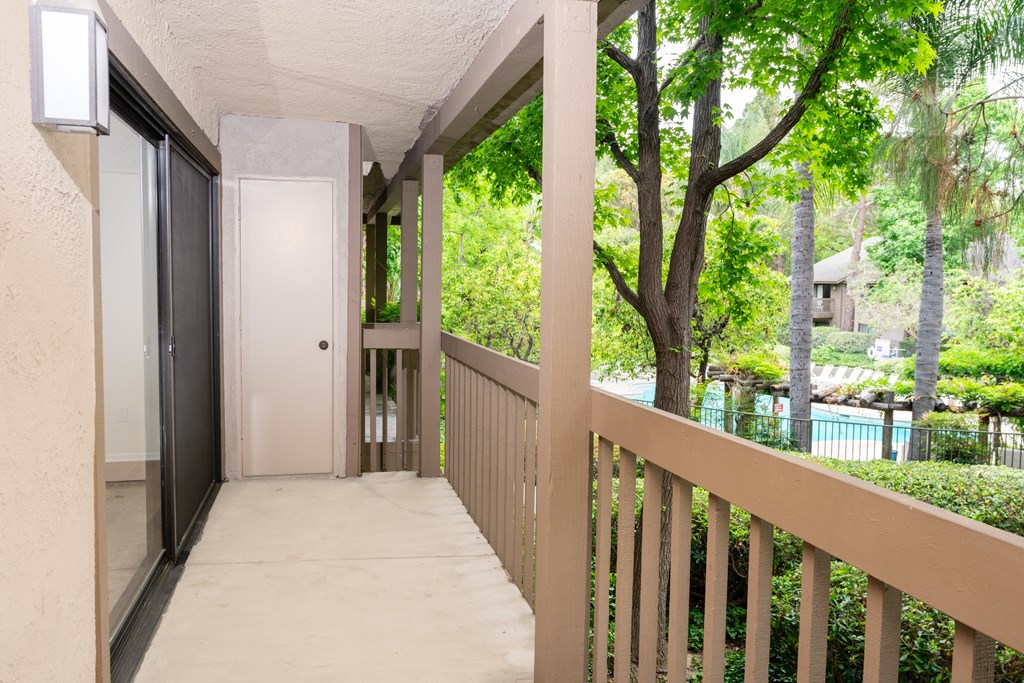 a balcony with a view of a yard and a door to a house