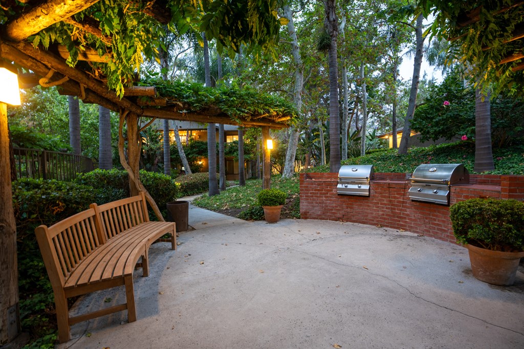 a patio with a bench and barbecue grill