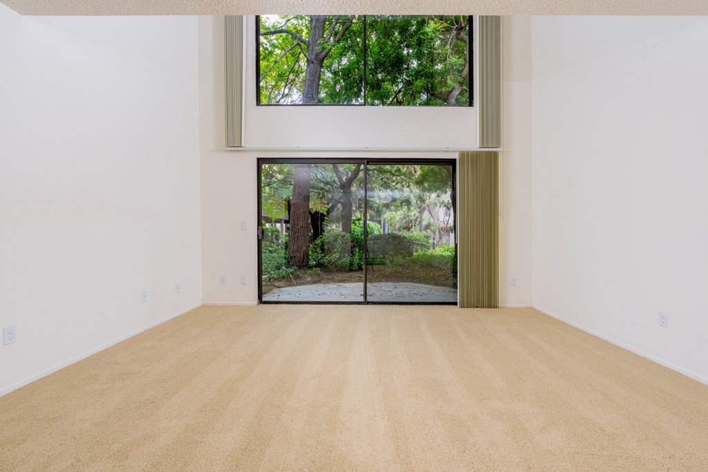 an empty room with a window and a door to a garden