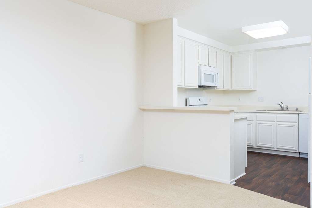 an empty kitchen with white cabinets and a counter