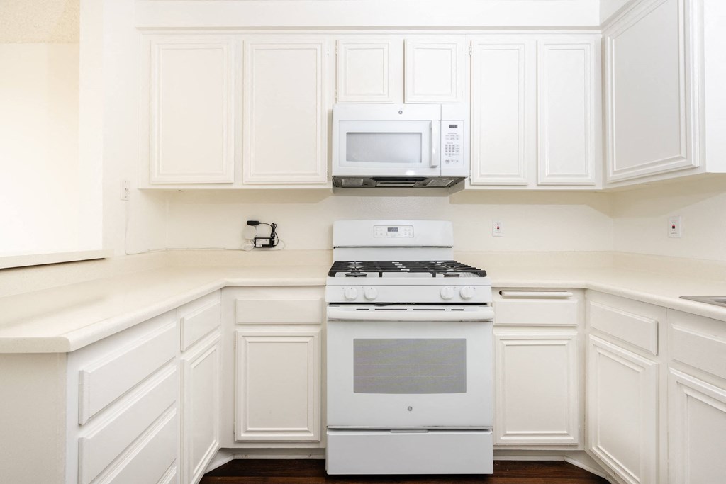 a kitchen with white cabinets and a white stove and microwave
