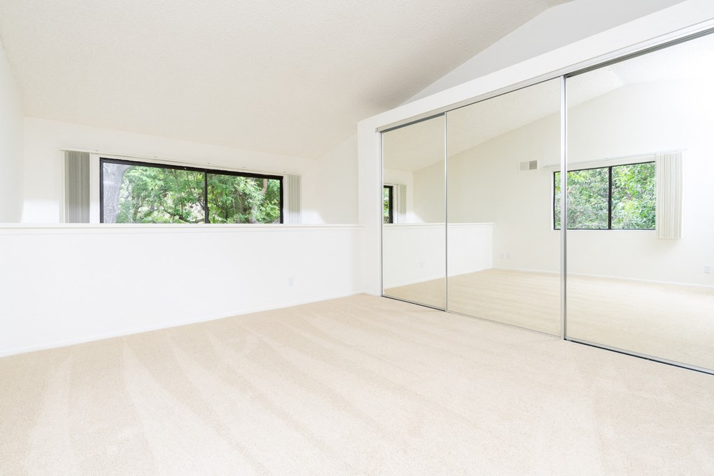 a large white room with a large window and a mirrored door