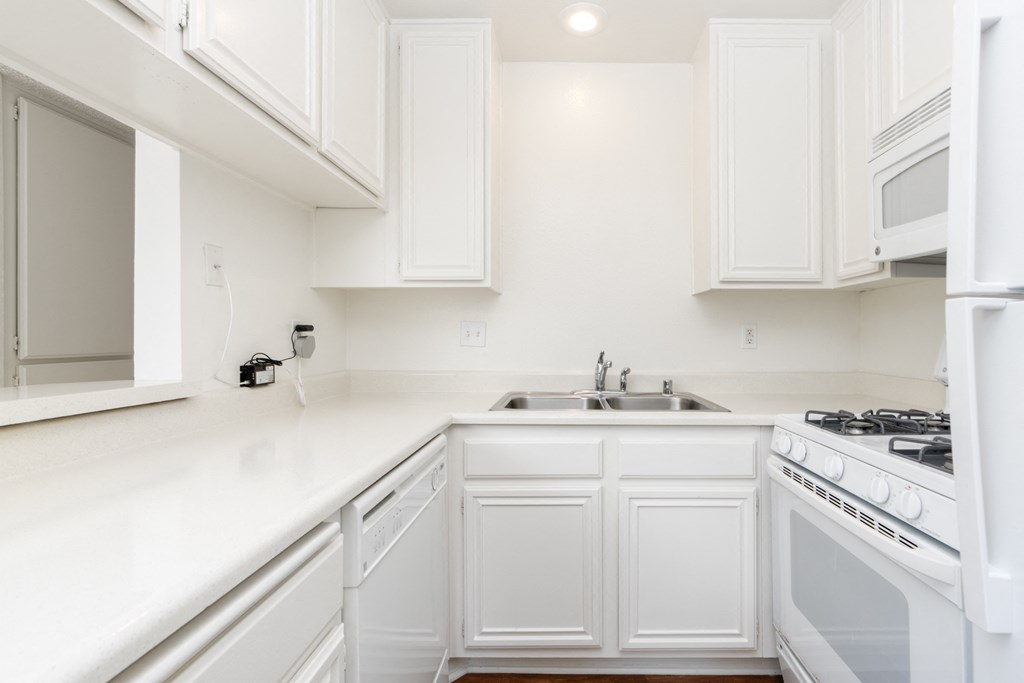 a kitchen with white cabinets and a stove and sink