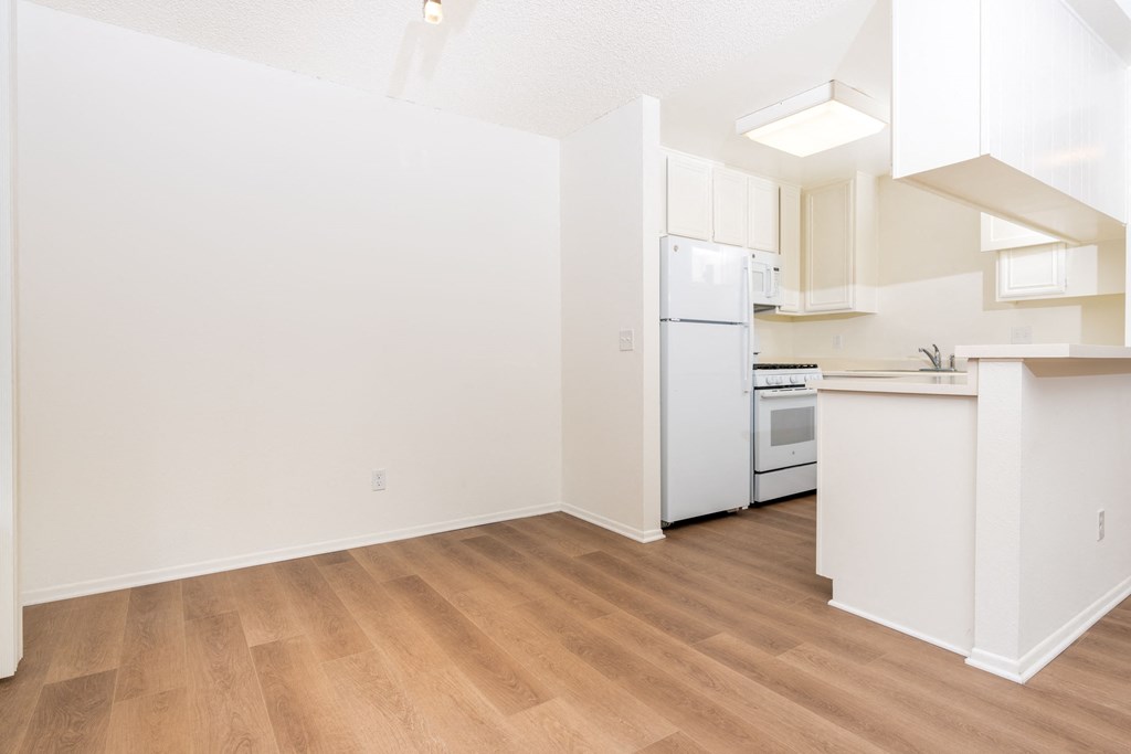 an empty kitchen with white appliances and a wood floor