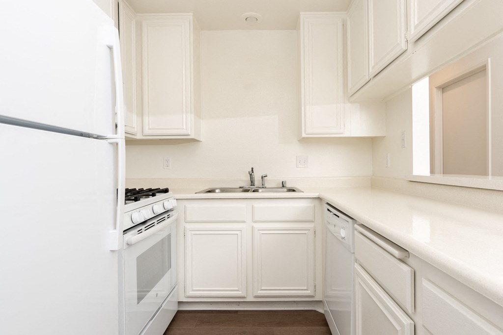 a kitchen with white cabinets and a sink and a refrigerator