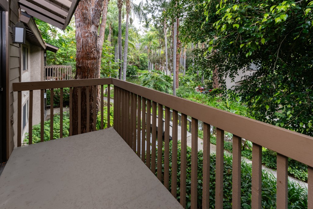 a balcony with a wooden railing and a view of the woods