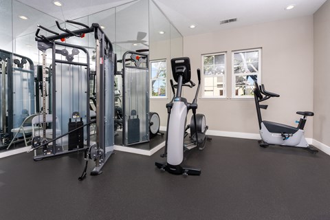 a gym with cardio equipment and weights on the floor