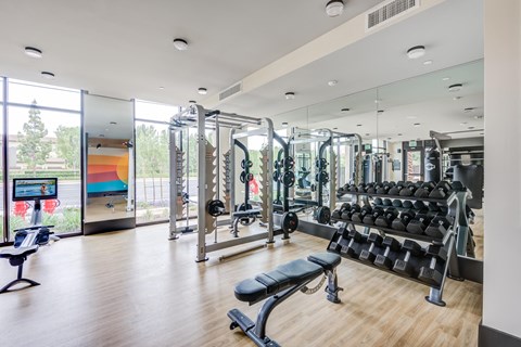 a view of the fitness center with weights machines and a pool in the background