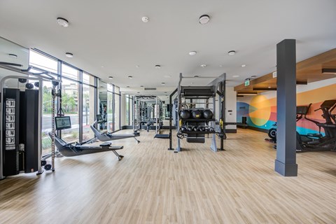 a spacious fitness room with hardwood floors and large windows