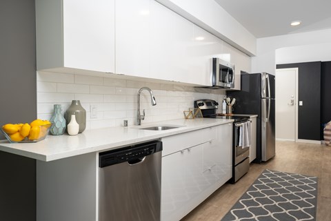 A modern kitchen with white cabinets and stainless steel appliances.