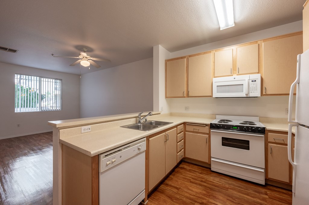 an empty kitchen with white appliances and wooden cabinets