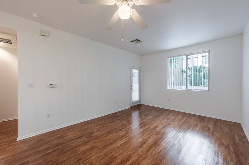 the living room of an empty house with wood flooring and a ceiling fan