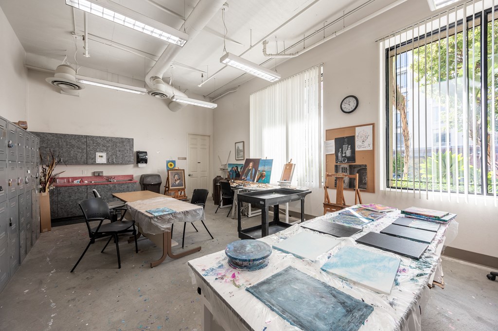 an art studio with tables and chairs and paintings in front of windows