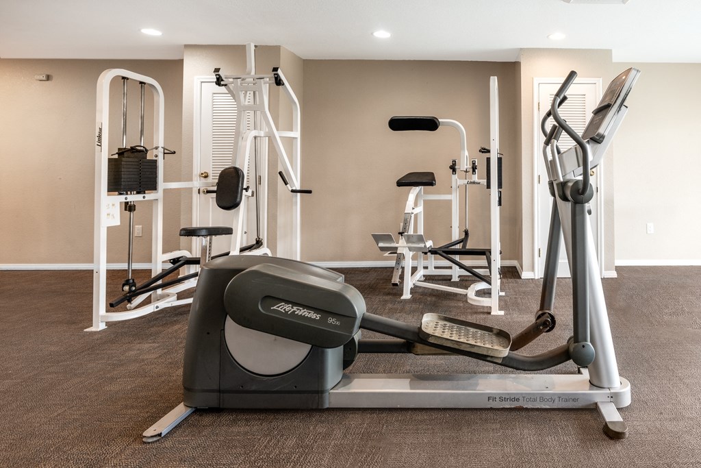 a gym with cardio equipment and weights on the floor