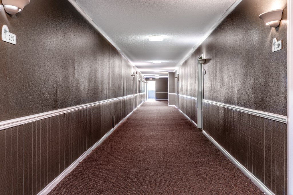 a hallway with wood paneled walls and a red carpet