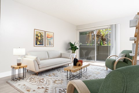 A living room with a white couch, a green chair, and a rug.