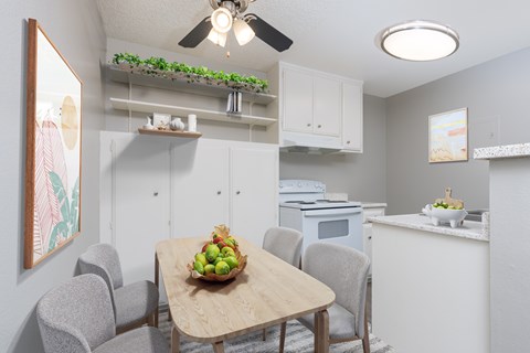A kitchen with a table and chairs and a bowl of fruit on the table.