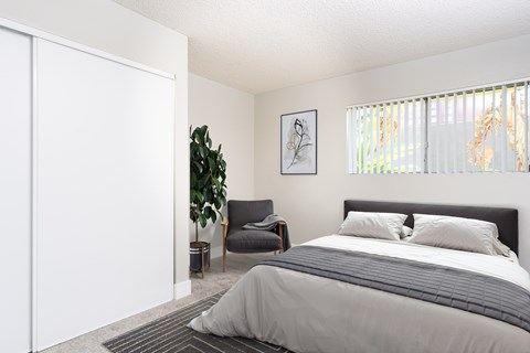 A bedroom with a large bed and a chair.