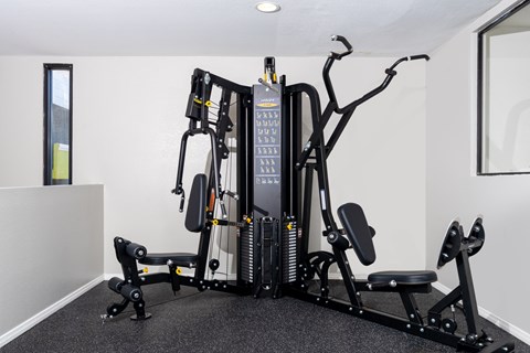 A black and grey gym machine sits in a white room.