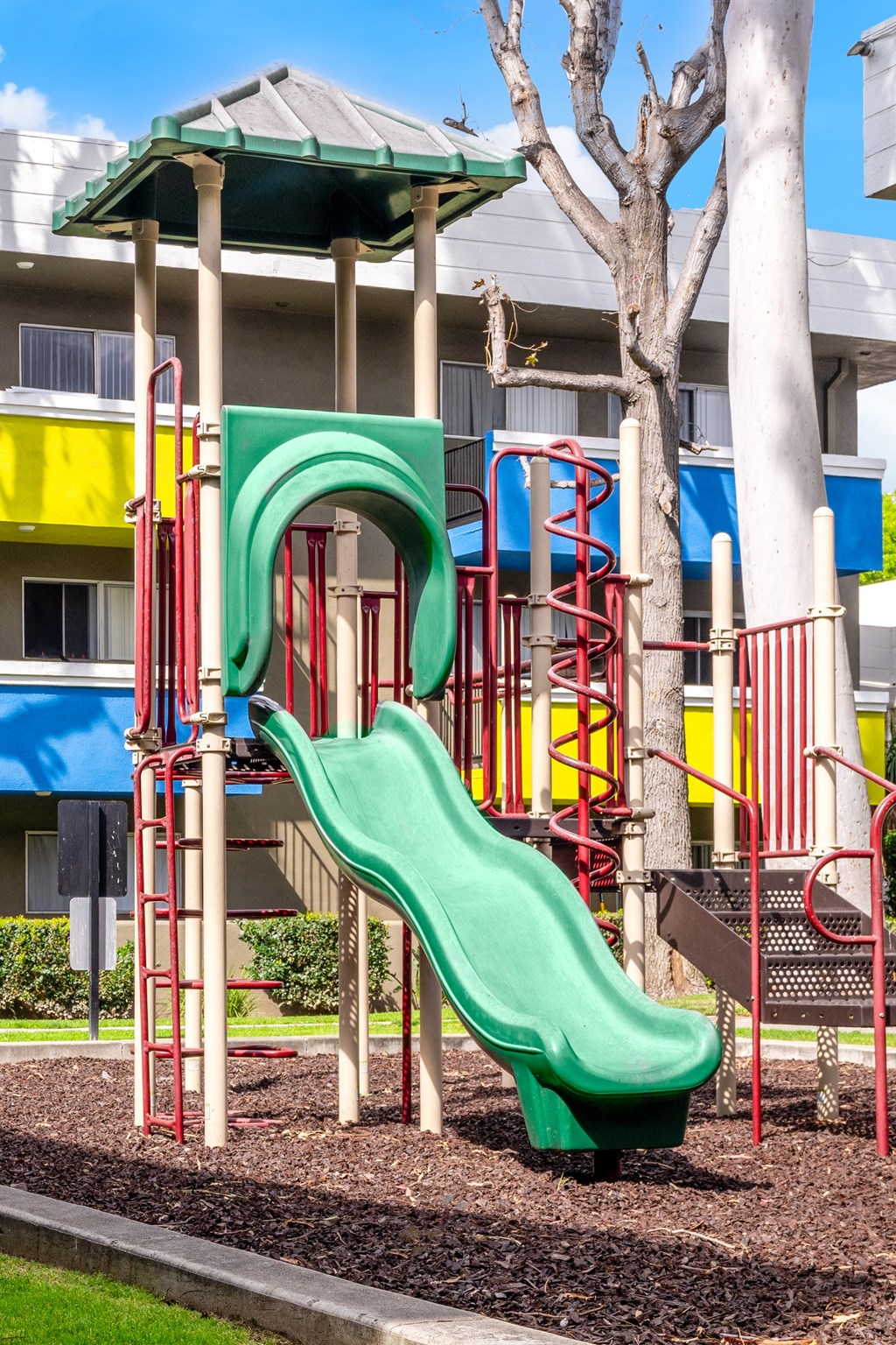 a playground with a green slide in front of a building