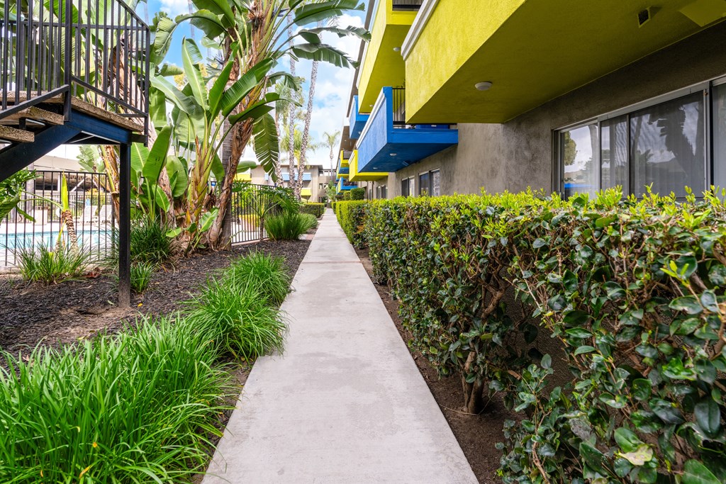 a walkway between two buildings with plants on either side