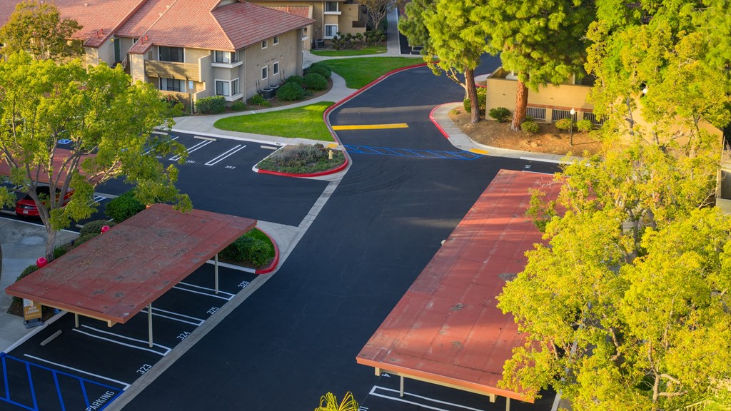 A parking lot with a red roofed structure and a building in the background.