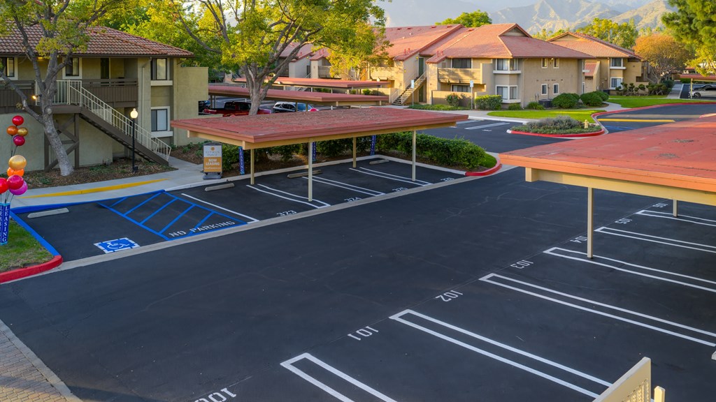 A parking lot with a red roofed structure and a blue painted parking space.