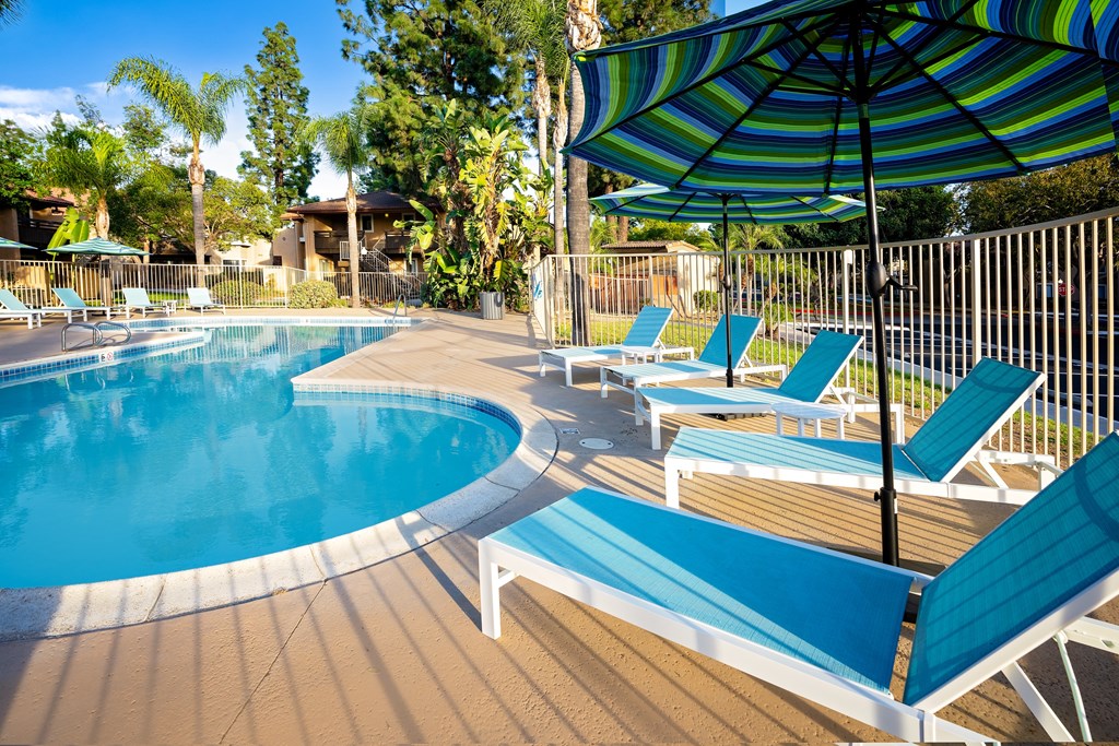 A pool with a blue umbrella and blue chairs.