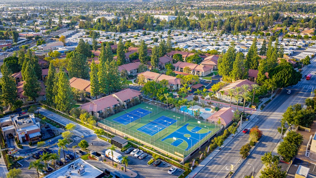 A tennis court with the number 36 on it is surrounded by houses and trees.
