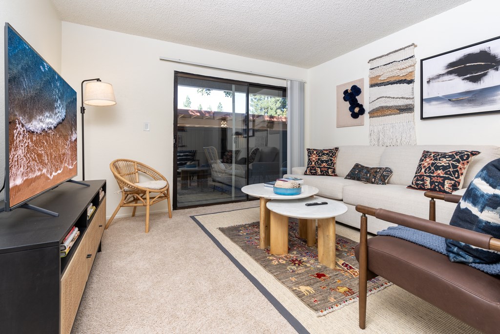 A living room with a flat screen TV and a brown leather couch.