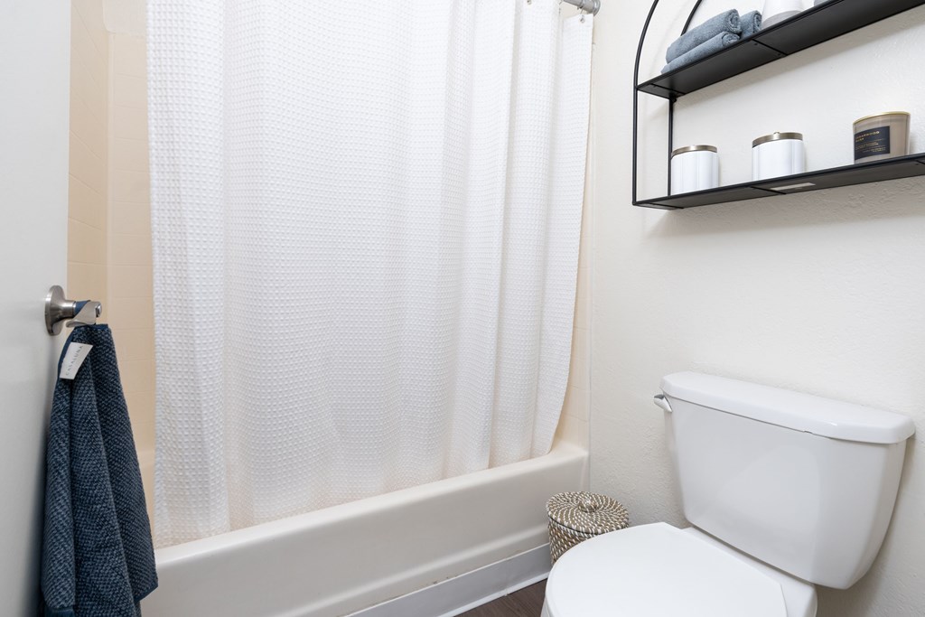 A white toilet sits next to a white bathtub with a blue towel hanging on the tub.