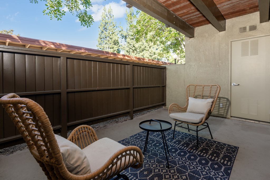 A patio with a wicker chair and a small table.