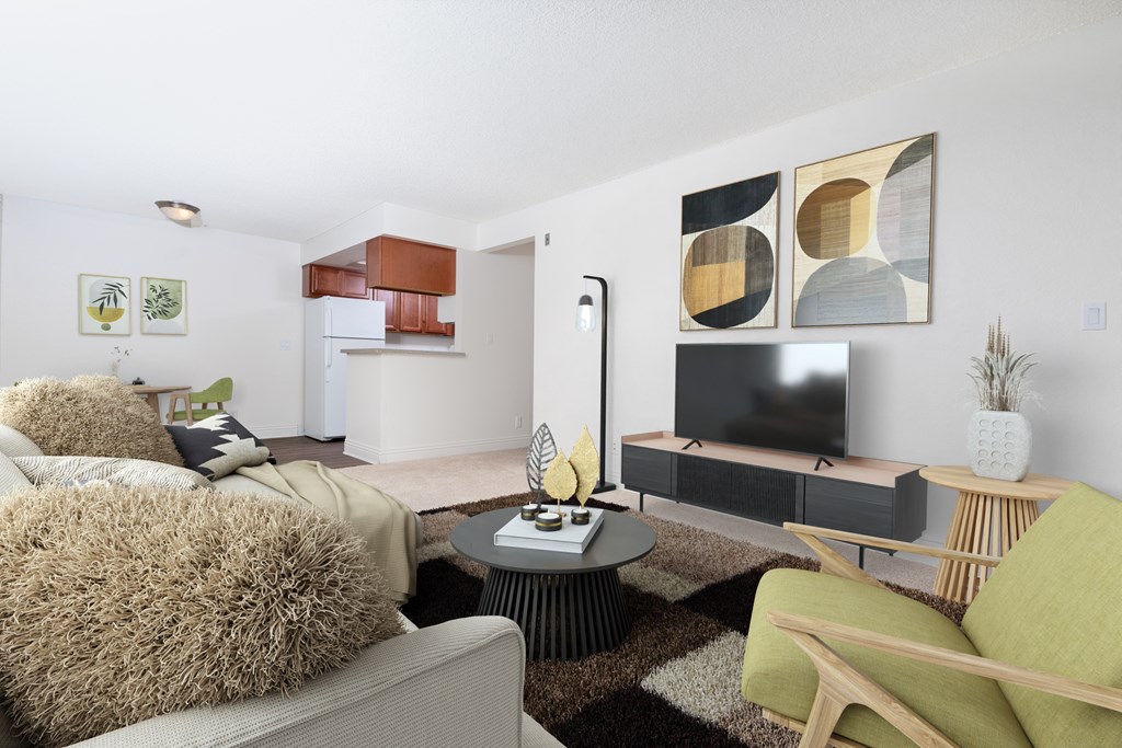 A living room with a grey couch, a green chair, a black coffee table, a flat screen TV, and a painting on the wall.