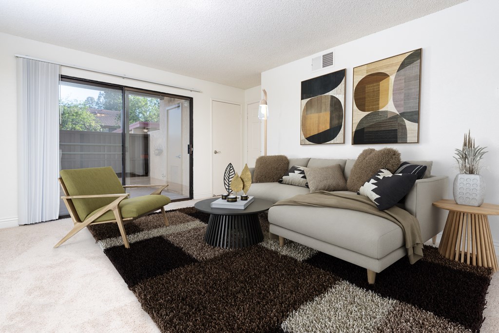 A living room with a couch, chair, and two abstract paintings on the wall.