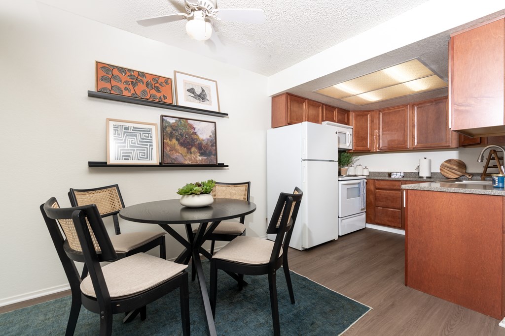 A kitchen with a table and chairs in the foreground and a refrigerator in the background.