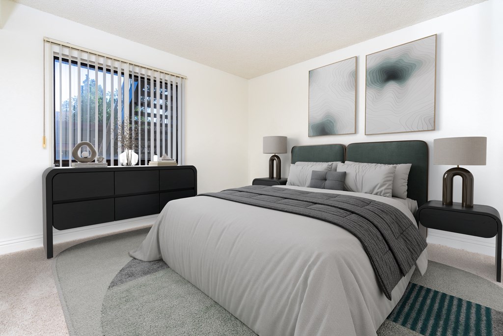 A bedroom with a large bed and a window with blinds.
