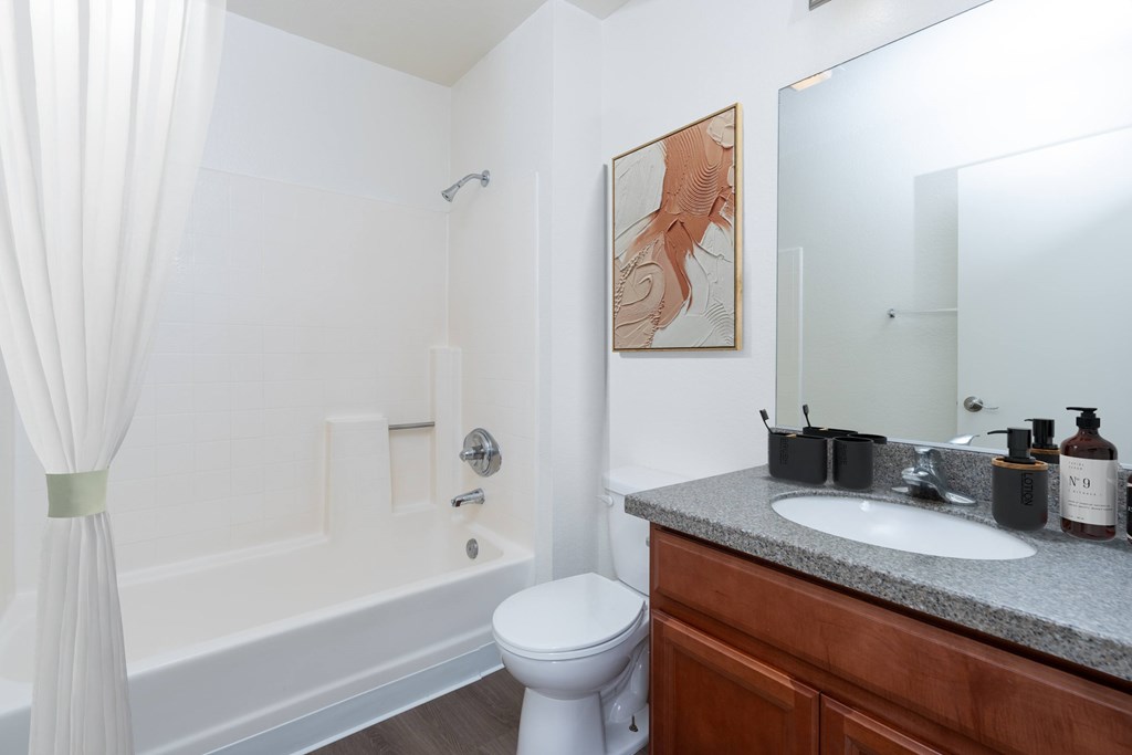 A white bathroom with a toilet, sink, and a large mirror.