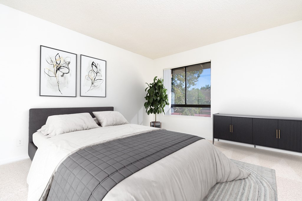A bedroom with a large bed and two framed pictures on the wall.
