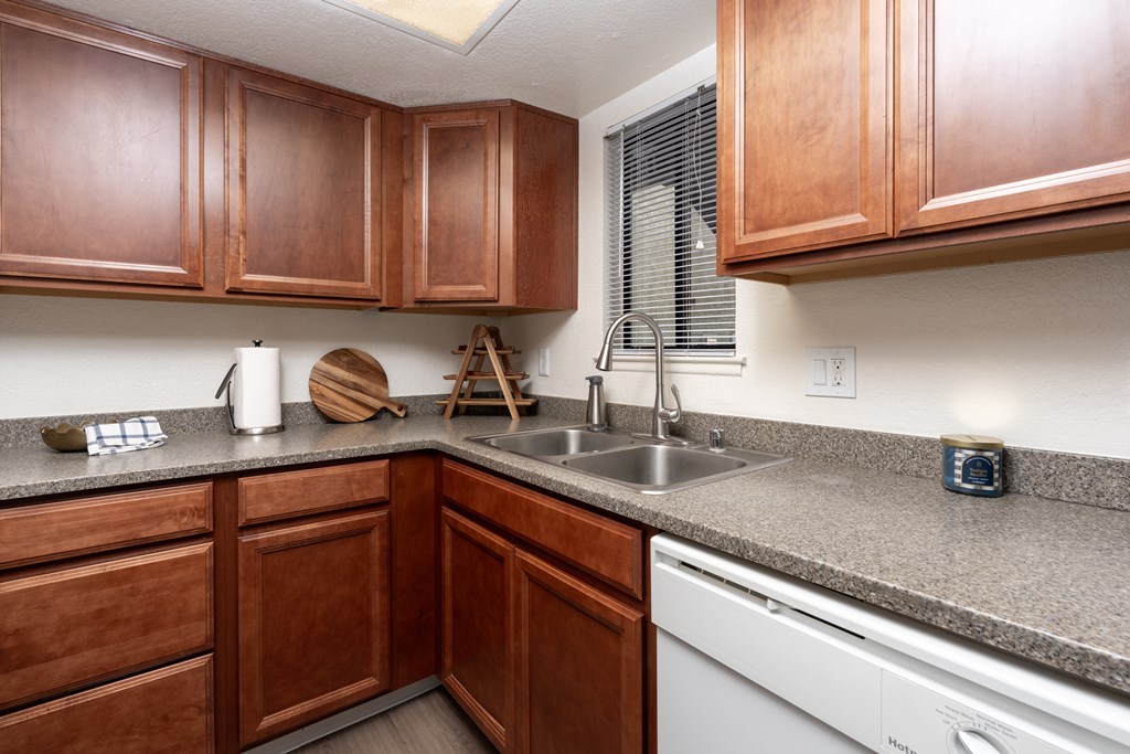 A kitchen with wooden cabinets and a white dishwasher.