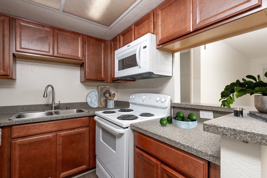A kitchen with a white stove and wooden cabinets.