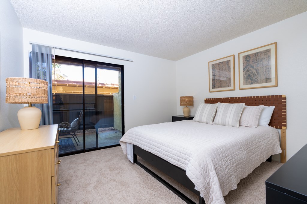 A bedroom with a large bed, a nightstand, and a chair.