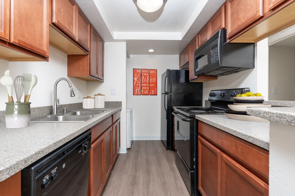 A kitchen with black appliances and wooden cabinets.