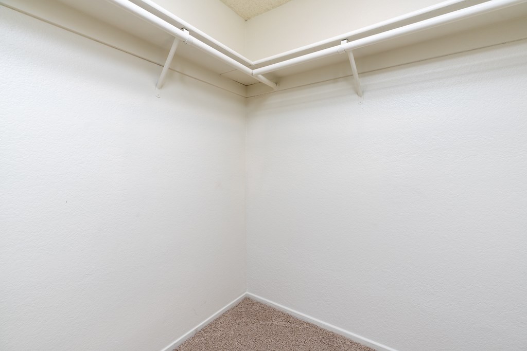 A corner of a room with white walls and a carpeted floor.